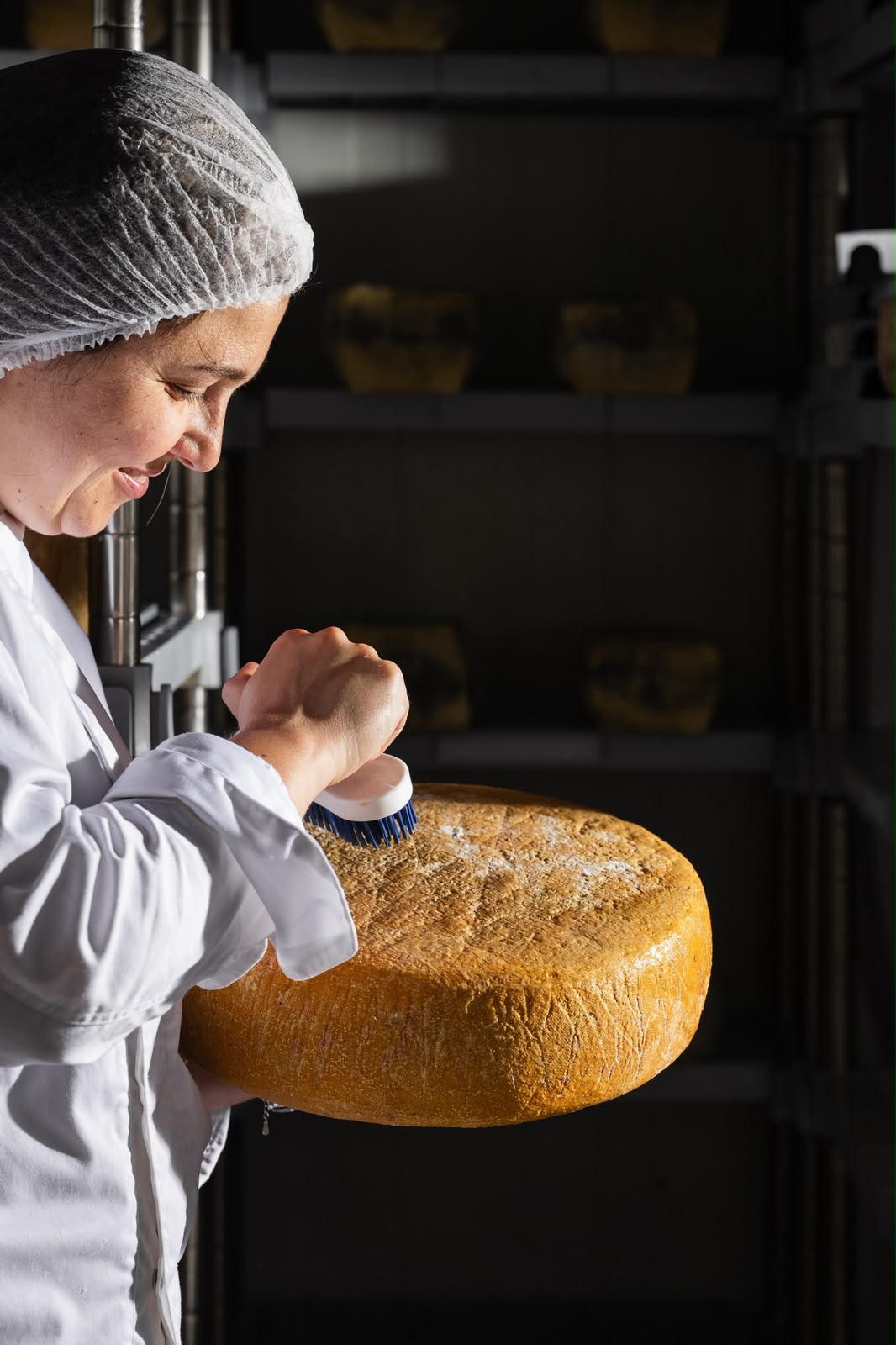 Naomi Richard Stein brushing an ageing wheel of cheese in the GVINAGE ageing cellar